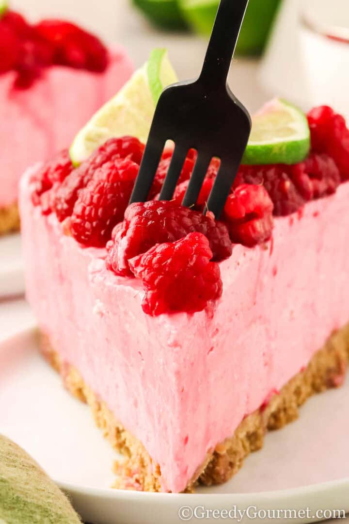 Slice of raspberry cheesecake on a white plate.