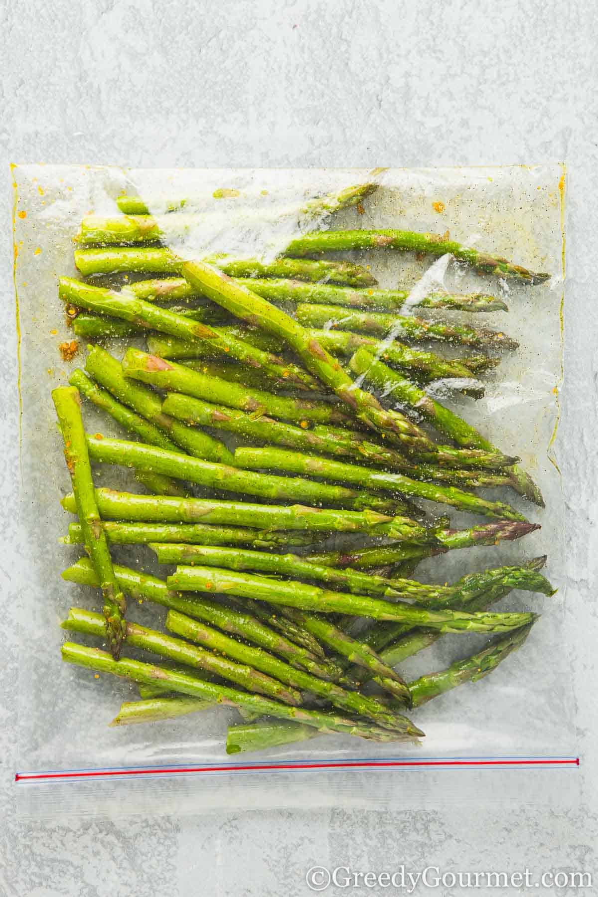Seasoning asparagus in a plastic bag.